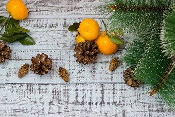 Mandarin fruits, branches of a Christmas tree and cones on a rustic background. Christmas holidays concept