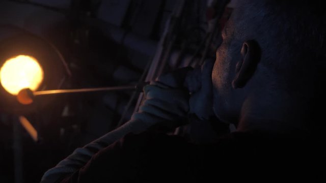 Glassblower free blowing glass at glassblowing factory