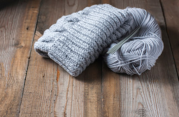 Fototapeta na wymiar wool grey hat, knitting needles and yarn on wooden background