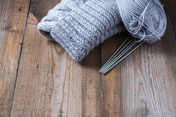 Fototapeta na wymiar wool grey hat, knitting needles and yarn on wooden background.
