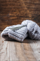Fototapeta na wymiar wool grey hat, knitting needles and yarn on wooden background.