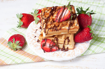 Freshly baked belgium waffles with chocolate sauce and strawberr