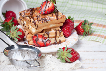 Freshly baked belgium waffles with chocolate sauce and strawberr