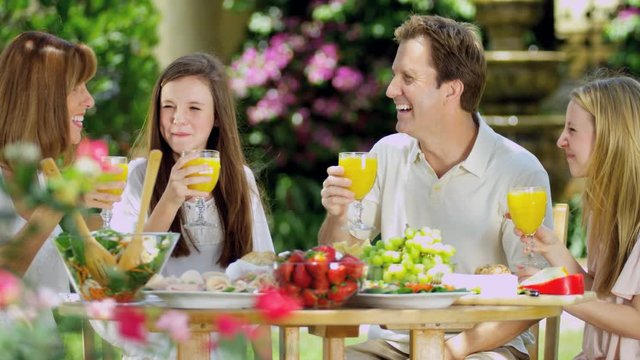 Young American family with teen daughters drinking fruit juice and enjoying healthy organic lunch at home RED EPIC