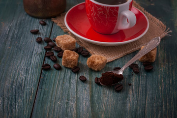Red cup of coffee on wooden background, coffee beans and sugar o