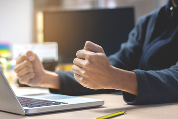 Close-up Business man with raised fists sitting at her desk. Celebrating Success .