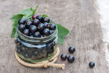 fresh black currant in the glass, on rustic wooden board.