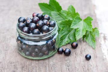fresh black currant in the glass, on rustic wooden board.