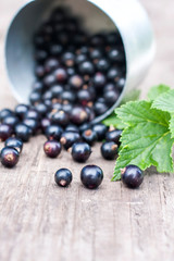 fresh black currant in the glass, on rustic wooden board.