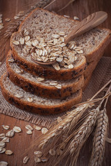 Fototapeta na wymiar Healthy wholegrain bread on burlap napkin, located on wood back