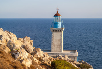 Lighthouse above the sea on a rocky cape at sunset.Mani peninsula, Cape Tenaro. Photo taken September 2018.