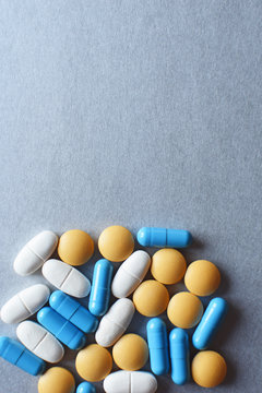 Different medical pills and capsules on silver color grey background with copy space for text top view. Pharmacy, healthcare and addiction concept.