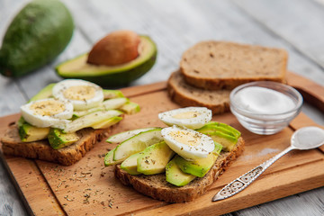 two avocado sandwiches with egg and spices on a wooden Board