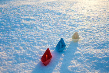 Red, blue and white paper boat in the snow