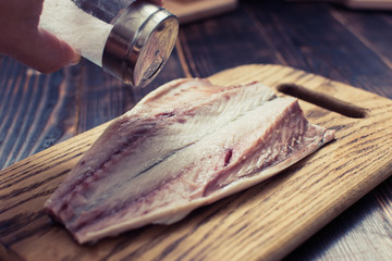 Fresh mackerel fish fillet sprinkled with salt on a wooden background. Cooking, cutting fish for cooking.