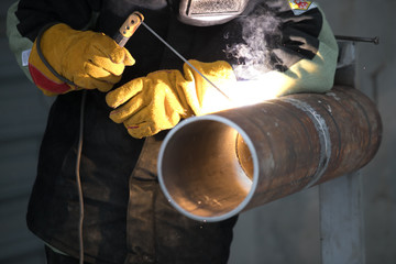 Worker welding metal piping using tig welder
