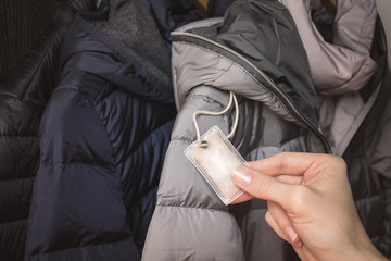 Female hand holding a small transparent plastic bag with winter jacket's filling (down) sample. Choosing qualitative filling for winter clothes.