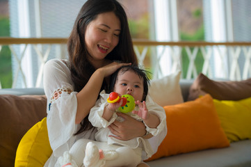 young happy beautiful Asian Korean woman playing with baby girl sitting at holidays resort enjoying vacation trip in mother and little daughter love