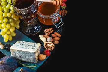 dor blue cheese with figs, grapes, nuts and honey on a shale board isolated on a black background, Flat lay, Copy space