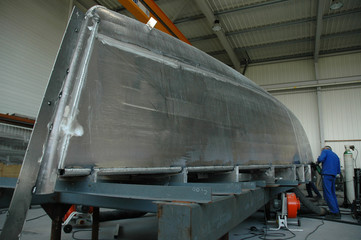 Employed in overalls working on the overturned hull of a ship under construction