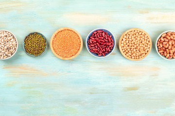 An overhead photo of various legumes on a teal background with copy space. Red kidney and pinto...