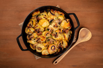 A photo of a braiser with cooked vegetables, potato, green peas, mushrooms, shot from above on a dark rustic background with copy space, a vegan dinner