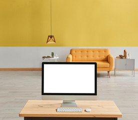 Yellow living room with yellow sofa and wooden lamp blur background, close up desktop screen on the wooden desk.