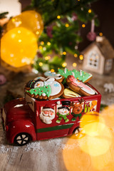 Holiday traditional food bakery. Decorative toy car with christmas Gingerbread cakes in cozy warm decoration with garland lights