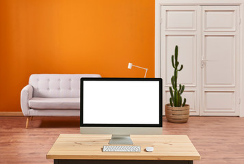 Orange living room, sofa and white classic door, close up desktop screen on the wooden desk.