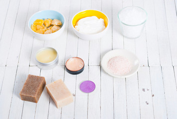 bath salts, beeswax , makeup base, powder compact, soaps and cosmetic creams on white wooden background