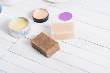 bath salts, beeswax , makeup base, powder compact, soaps and cosmetic creams on white wooden background