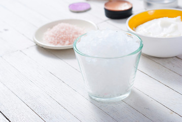 bath salts, beeswax , makeup base, powder compact, soaps and cosmetic creams on white wooden background