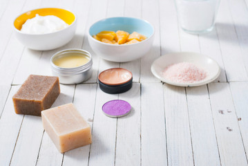 bath salts, beeswax , makeup base, powder compact, soaps and cosmetic creams on white wooden background