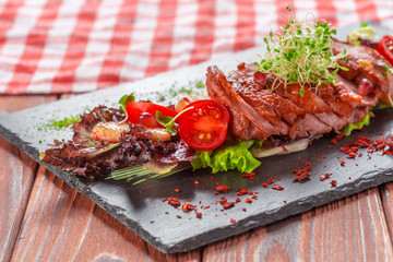 Tasty sliced roast duck breast with fresh vegetable salad closeup on a plate.