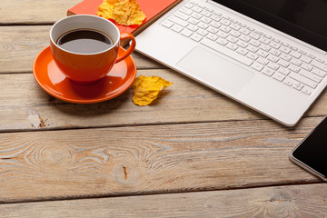 A cup of coffee on the orange plate on the wooden table. Office interior