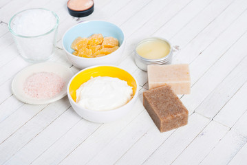 bath salts, beeswax , makeup base, powder compact, soaps and cosmetic creams on white wooden background