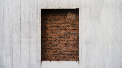 The beautiful sealed brick window in wooden wall for texture background with copy space, may use to interior design
