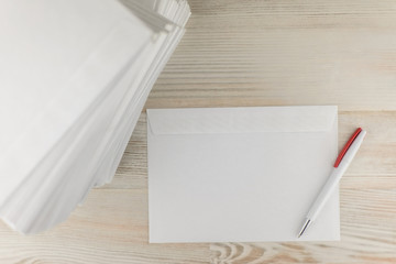 office work with correspondence: a Stack of blank envelopes on a wooden table, an envelope and a ballpoint pen lay next to