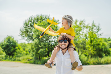 Happy father and son playing with toy airplane against old runway background. Traveling with kids concept