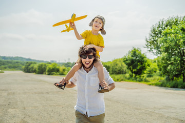 Happy father and son playing with toy airplane against old runway background. Traveling with kids concept