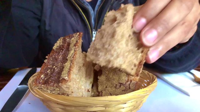 Woman Breaking Brown Bread with Her Hands.