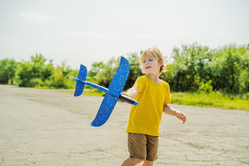 Happy kid playing with toy airplane against old runway background. Traveling with kids concept