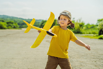 Happy kid playing with toy airplane against old runway background. Traveling with kids concept