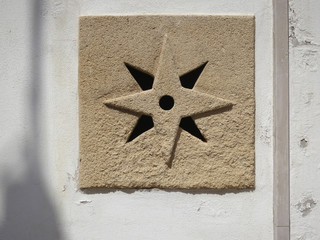 ventilation grid in the shape of a eight point star in a sandstone wall