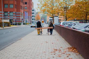 young man and woman on bikes carrying furniture packed in a cardboard box