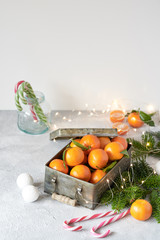 Christmas background-gray concrete, candy, Christmas tree, cinnamon, toys, sweet tangerines in a box. The view from the top, an empty space