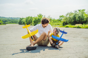 Happy father and son playing with toy airplane against old runway background. Traveling with kids concept