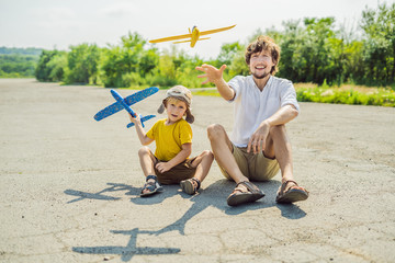 Happy father and son playing with toy airplane against old runway background. Traveling with kids concept