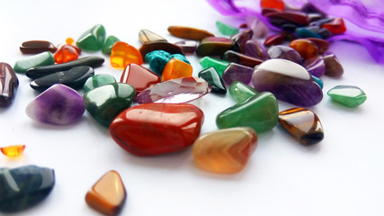 Assorted natural bright coloured semi precious gemstones and gems on white background
