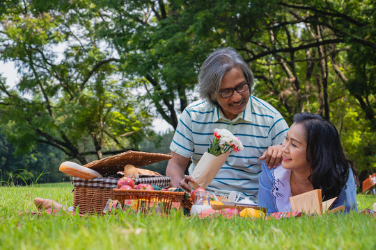 The old couple relax in park. In the morning Man hugging woman beside picnic basket.They are in love and sweet.Life style, Exercise ,Photo concept  love and healthy.